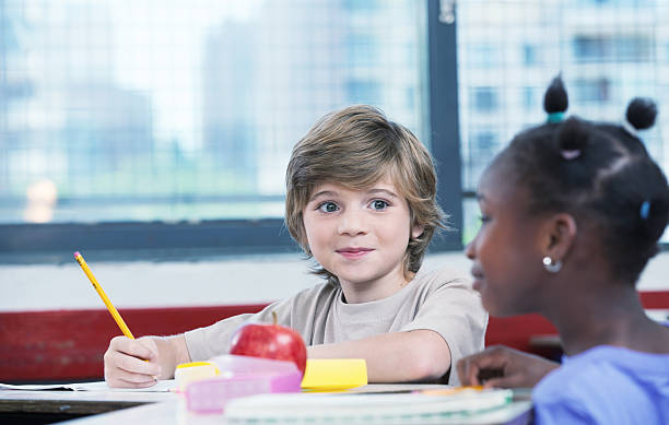 istock Cute caucasian kid at classroom desk drawing and smiling 534160511