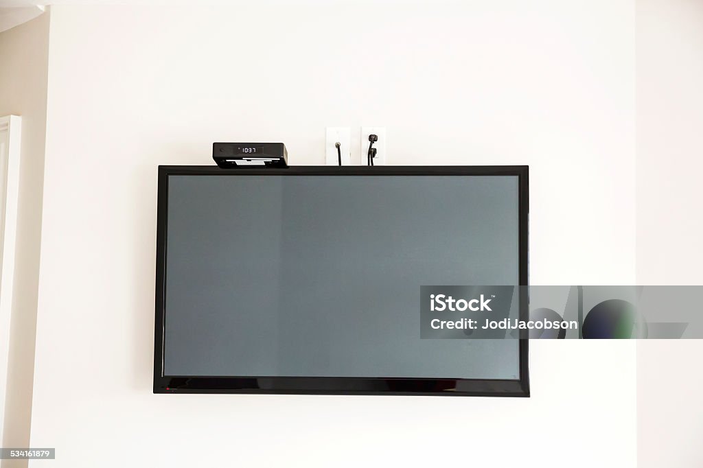 Flat screen television mounted on wall A flat screen television mounted on a wall with a cable box resting on top.  Shot with Canon 5D Mark 3.  rr Apartment Stock Photo