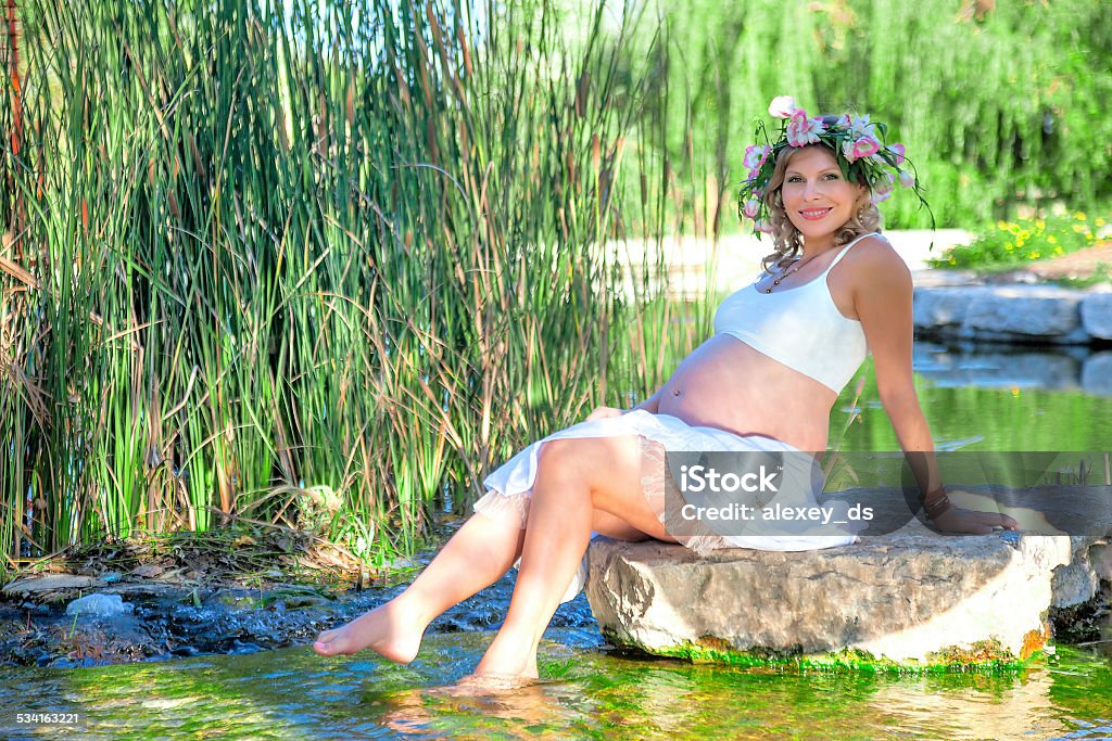 Pregnant woman sitting on the rock in the lake 20-24 Years Stock Photo
