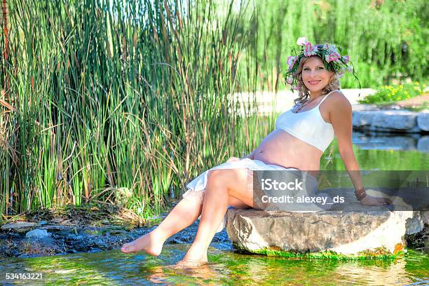 Pregnant Woman Sitting On The Rock In The Lake Stock Photo - Download Image Now - 20-24 Years, 2015, Adult