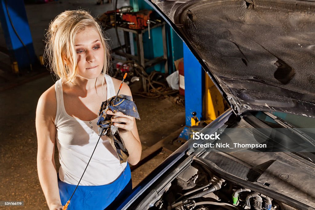 Girl checks the oil level in the car Girl checks the oil level in their own broken car 2015 Stock Photo