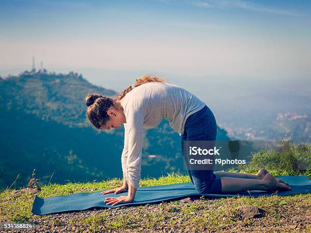 Sporty Fit Woman Practices Yoga Asana Marjariasana Outdoors Stock Photo - Download Image Now