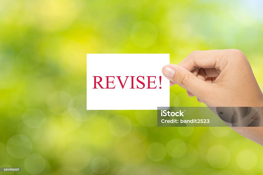 REVISE! Hand holding a paper REVISE! on green background Homework Stock Photo