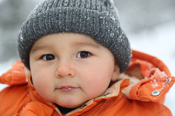istock Baby boy with snow and cap winter looking into camera 534193017