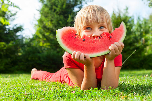 Child with slice of melon outdoor