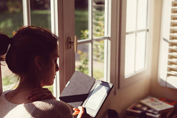 mujer en casa, leyendo libro electrónico - newspaper france photography horizontal fotografías e imágenes de stock