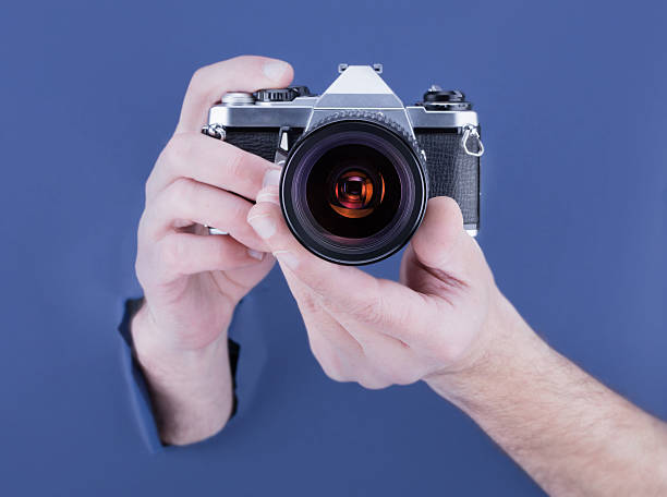istock Male hand breaking through the blue paper background  camera 534194736
