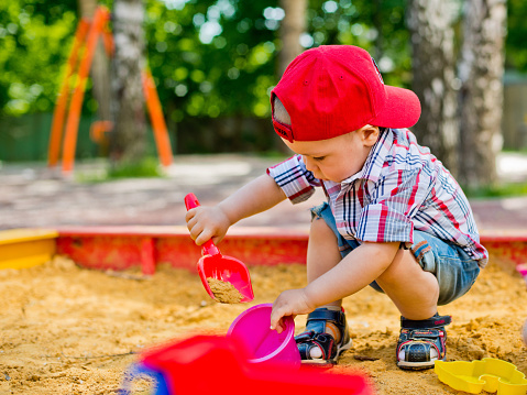 child playing in the sandbox with toy car