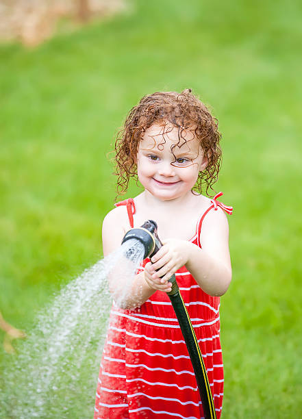 istock Young Girl Spraying With Garden Hose 534198563