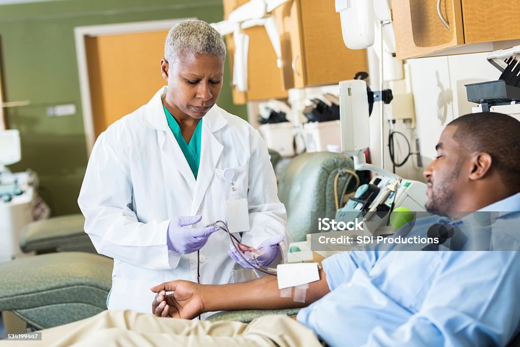 Phlebotomist checking line whle patient donates blood in hospital Blood Donation Stock Photo