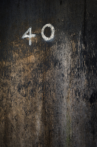 Dark, weathered wooden door with peeling black paint and the number 40 in handpainted white digits.