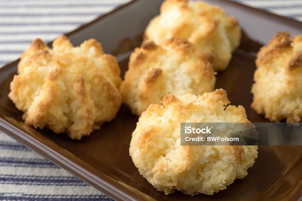 Close view of sugar free coconut macaroons in a dish A very close view of sugar free coconut macaroons in a small dish atop a blue striped tablecloth. Baked Stock Photo