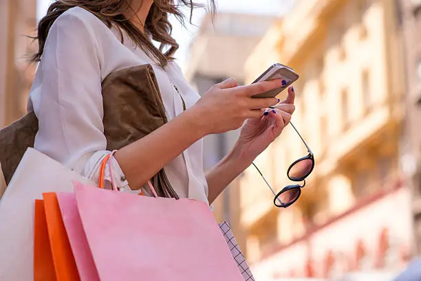 Photo of Women carrying shoppings bags and using smartphone