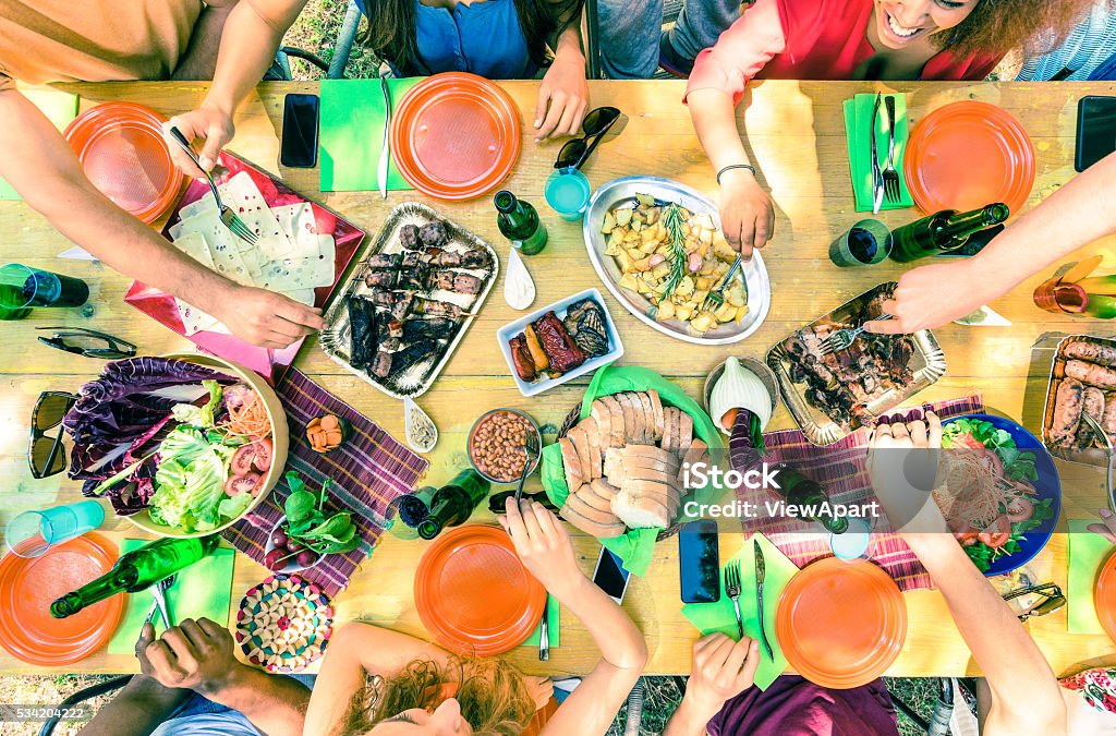 Top view of friend hands serving food at barbecue party Top view of friend hands serving food at barbecue garden party - Multiracial people group enjoying grill meal at backyard bbq meeting - Lunch and dinner concept outdoors - Vivid cross processed filter Table Stock Photo