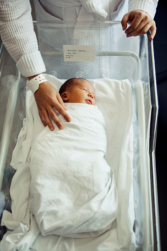 Newborn baby boy asleep in hospital bassinet