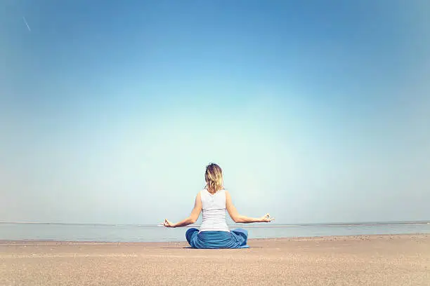 Photo of woman performing relaxation and meditation exercises at the sea