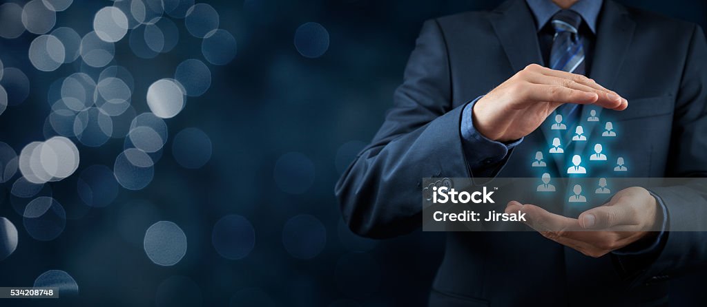 Customer or employees care concept Customer care, care for employees, life insurance and marketing segmentation concepts. Protecting gesture of businessman or personnel and icons representing group of people. Wide banner composition with bokeh background. Business Relationship Stock Photo