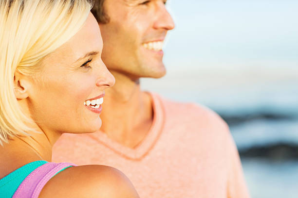 istock Happy Couple Looking Away On Beach 534210672