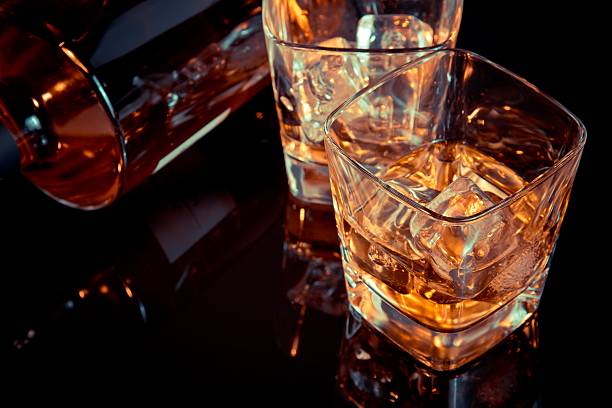 istock glass of whiskey near bottle on black table with reflection 534210914