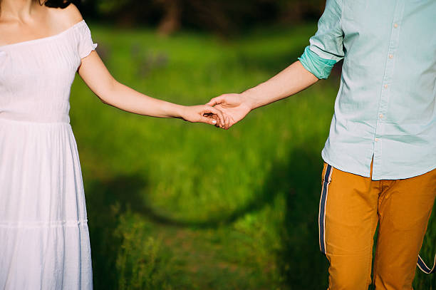 istock romantic couple holding hands gently.shadow of them on the grass 534211022
