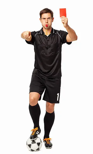 Full length portrait of soccer referee with ball showing red card while pointing over white background. Vertical shot.