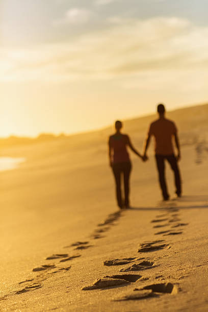 istock Couple Walking While Leaving Behind Track Of Footprints On Beach 534212138
