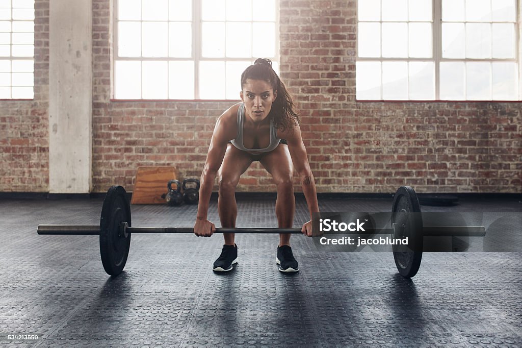 Female performing deadlift exercise with weight bar Female performing deadlift exercise with weight bar. Confident young woman doing weight lifting workout at gym. Weightlifting Stock Photo