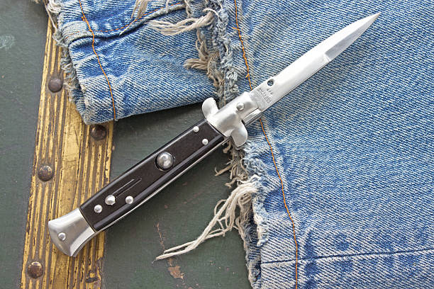 Switchblade knife on old blue jeans Switchblade knife on old blue jeans switchblade stock pictures, royalty-free photos & images