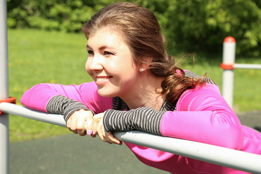 Fitness young woman in bright clothes stretching outdoors before running. Healthy lifestyle concept. Close up view.