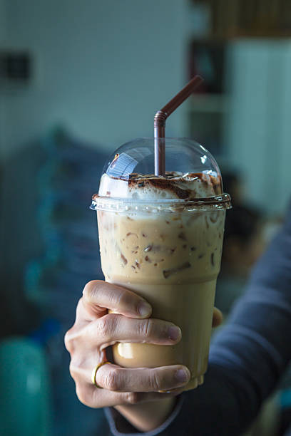 istock holding a Iced coffee in takeaway cup with tube 534220531