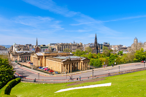 Aerial view of Calton Hill, Edinburgh sunset aerial view, Gothic Revival architecture in Scotland, View of Edinburgh city center from Calton Hill\n\nCalton Hill is a hill in central Edinburgh, Scotland, situated beyond the east end of Princes Street and included in the city's UNESCO World Heritage Site. Views of, and from, the hill are often used in photographs and paintings of the city.\nCalton Hill is the headquarters of the Scottish Government, which is based at St Andrew's House, on the steep southern slope of the hill. The Scottish Parliament Building and other prominent buildings such as Holyrood Palace lie near the foot of the hill. Calton Hill is also the location of several monuments and buildings: the National Monument, the Nelson Monument, the Dugald Stewart Monument, the old Royal High School, the Robert Burns Monument, the Political Martyrs' Monument and the City Observatory.\nThe area lies between the Edinburgh districts of Greenside and Abbeyhill.\n\nEdinburgh is the capital city of Scotland and one of its 32 council areas. The city is located in south-east Scotland, and is bounded to the north by the Firth of Forth estuary and to the south by the Pentland Hills. Edinburgh had a population of 506,520 in mid-2020, making it the second-most populous city in Scotland and the seventh-most populous in the United Kingdom.