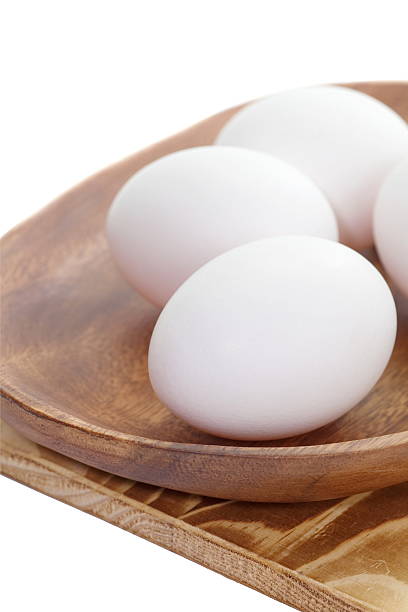 istock White egg in brown wooden plate on white background 534222377