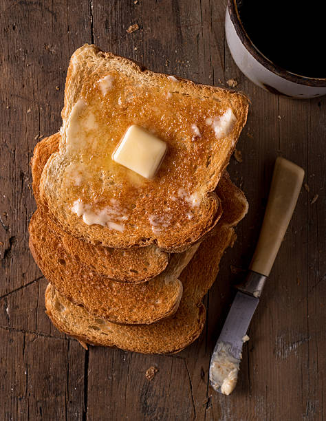 Buttered Toast Crusty buttered toast slices on a rustic tabletop with coffee. toasted bread stock pictures, royalty-free photos & images