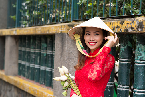 Portrait of attractive young lady in traditional Vietnamese dress and conical hat