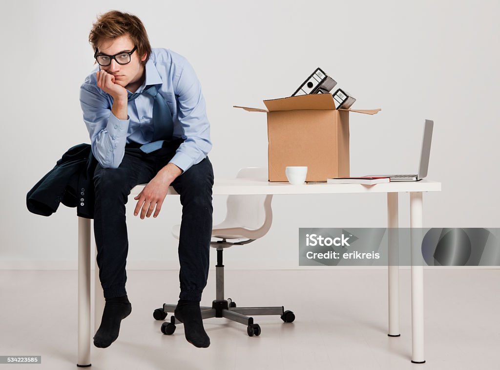 Being fired Young man sitting on the desk after being fired 2015 Stock Photo