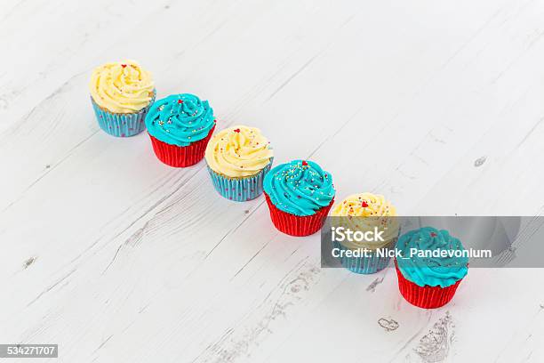 Tasty Looking Cupcakes Aligned On Bleached White Wooden Surface Stock Photo - Download Image Now