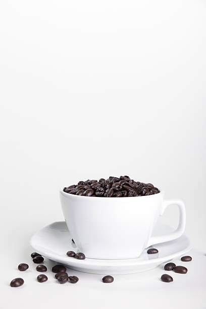Filiżanka kawy i ziarna na białym tle. – zdjęcie