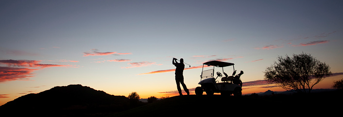 A male caucasian golfer swinging a golf club at dusk. Image taken in Arizona, United States, Panorama. The phoenix and Scottsdale region is one of the world's great golf destinations. There are well over a hundred beautiful desert golf courses in this region, which is known as the valley of the sun. 