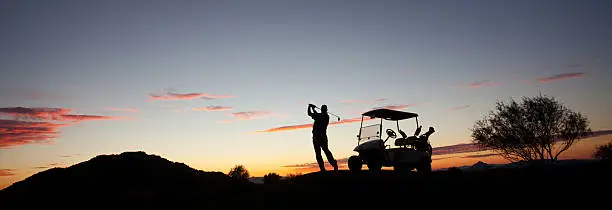 Photo of Male Caucasian Golfer Swinging A Golf Club with Cart