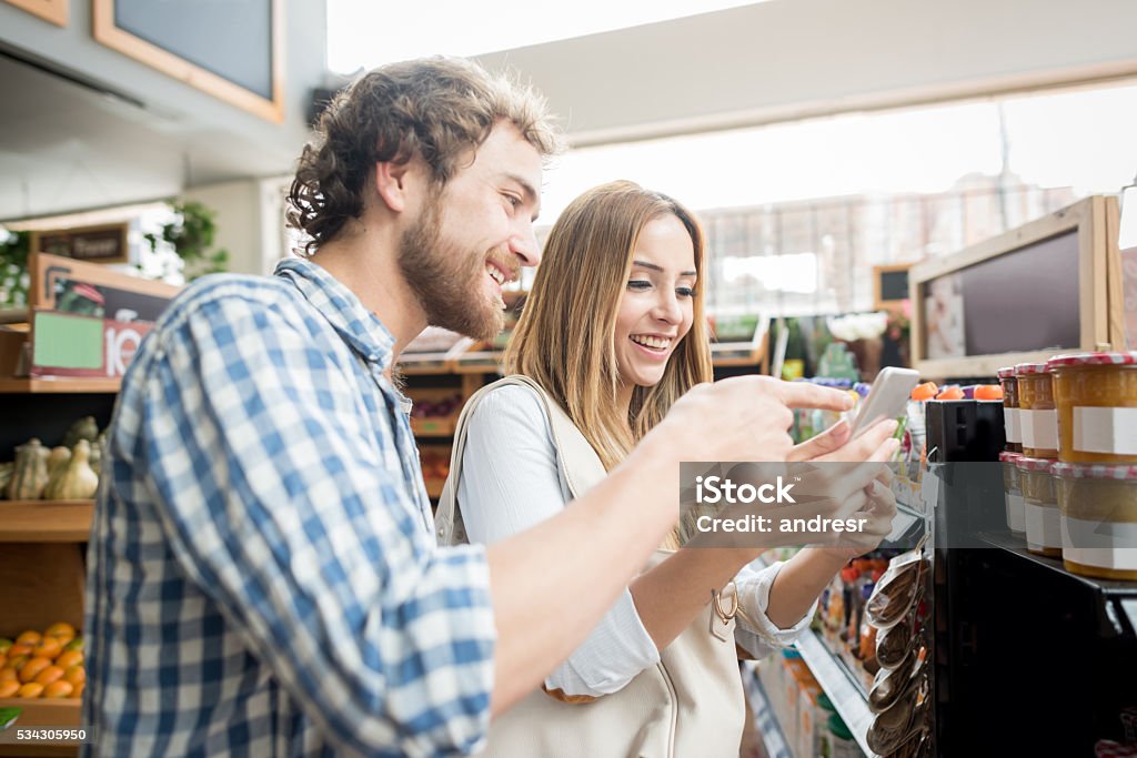Couple à l’épicerie passant par une liste de courses - Photo de Commerce libre de droits
