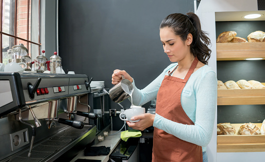 Woman working at a cafe and serving a cup of coffee