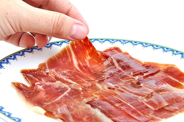 Man's hand holding an spanish serrano ham slice