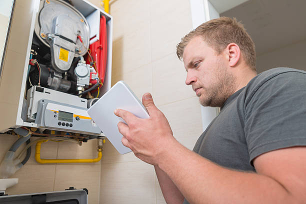 Technician repairing Gas Furnace using digital tablet stock photo