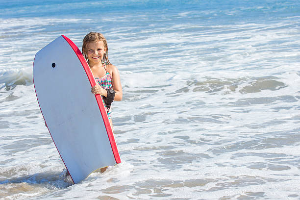 istock Cute girl playing with a boogie board in the ocean 534307453