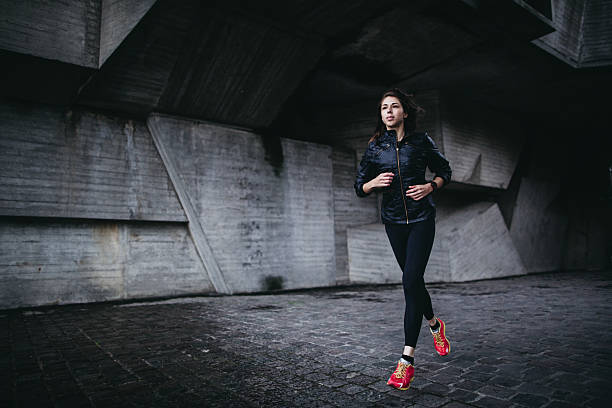 jeune femme sportive jogging extérieure - courir sous la pluie photos et images de collection