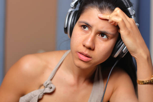 Teenage girl sitting at a wall listening to music opposite the window