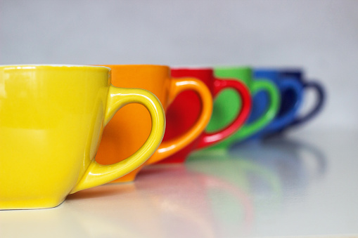 Cups of coffee lined up making a rainbow.