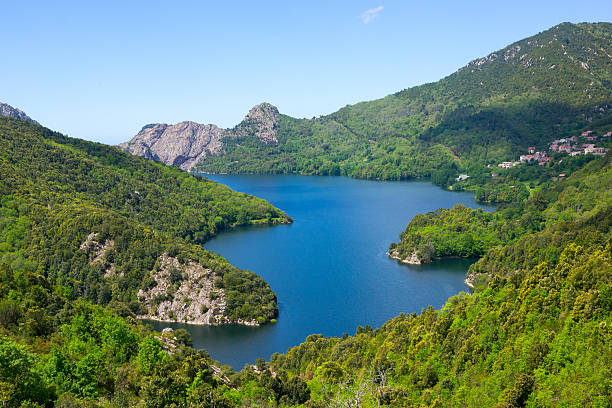 Lac de Tolla, Corsica in Mai. Deep green trees surround the blue lake with its crystal clear water.