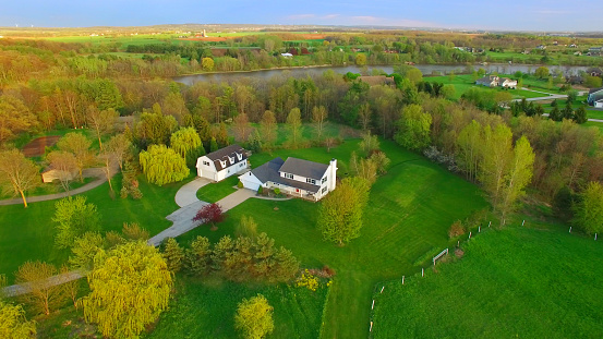 Evening aerial view of scenic rural home surrounded by trees in Springtime.