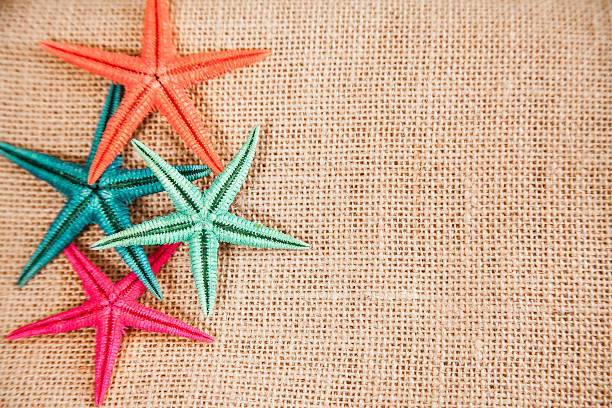 istock Summer vacation.  Colorful starfish on burlap background. 534322314
